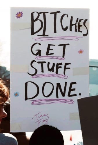 Photo of a sign that reads, "Bitches Get Stuff Done -- Tina Fey" The letters for 'Bitches' get increasingly smaller and squished because of space limitations on the sign.